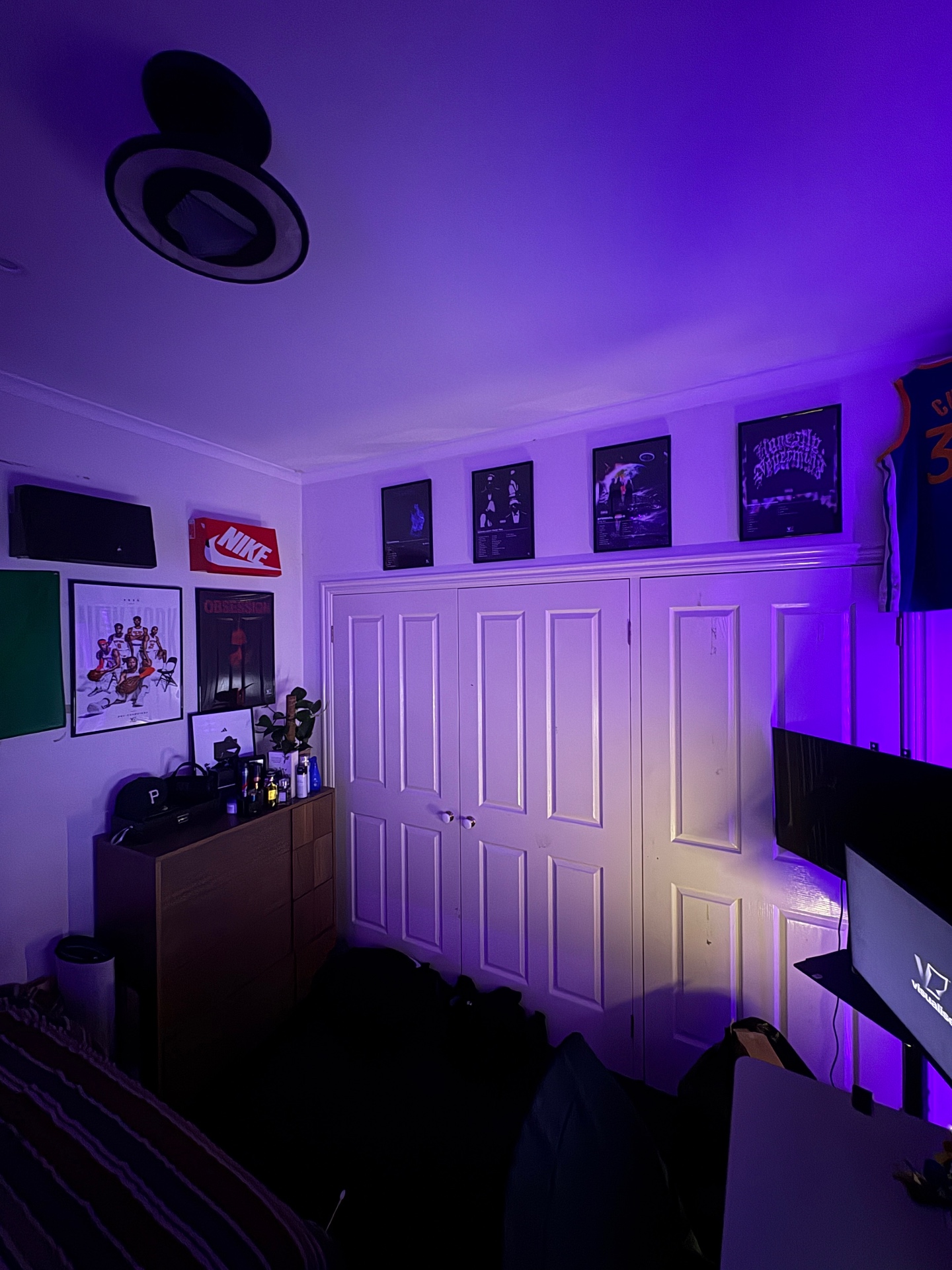 Bedroom gallery wall with VISUALISE album cover posters under purple LED lighting